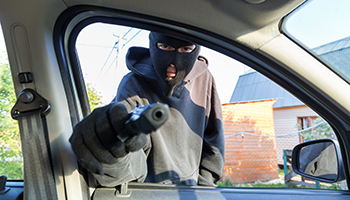 An armed man in the mask threatening pistol to the driver of the car